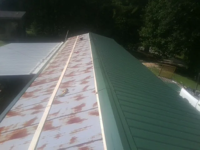 Old rusted panels beside newly installed green metal roofing — Wind Damage Roof Repair by Roofing Brothers in Bucyrus
