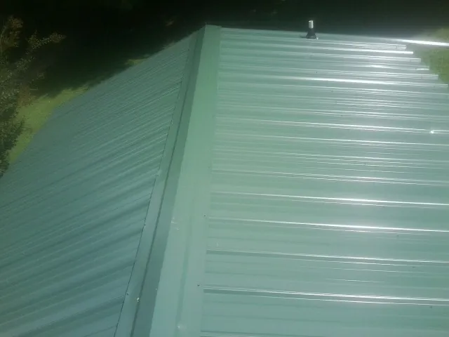 New green metal panels meeting at the ridge of a roof — Flat Roof Repair work by our crew in Bucyrus