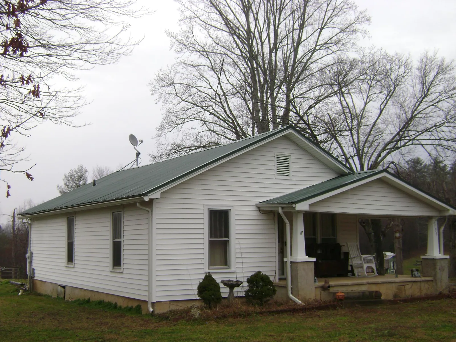 Green metal roof on a white bungalow with a side porch in Bucyrus