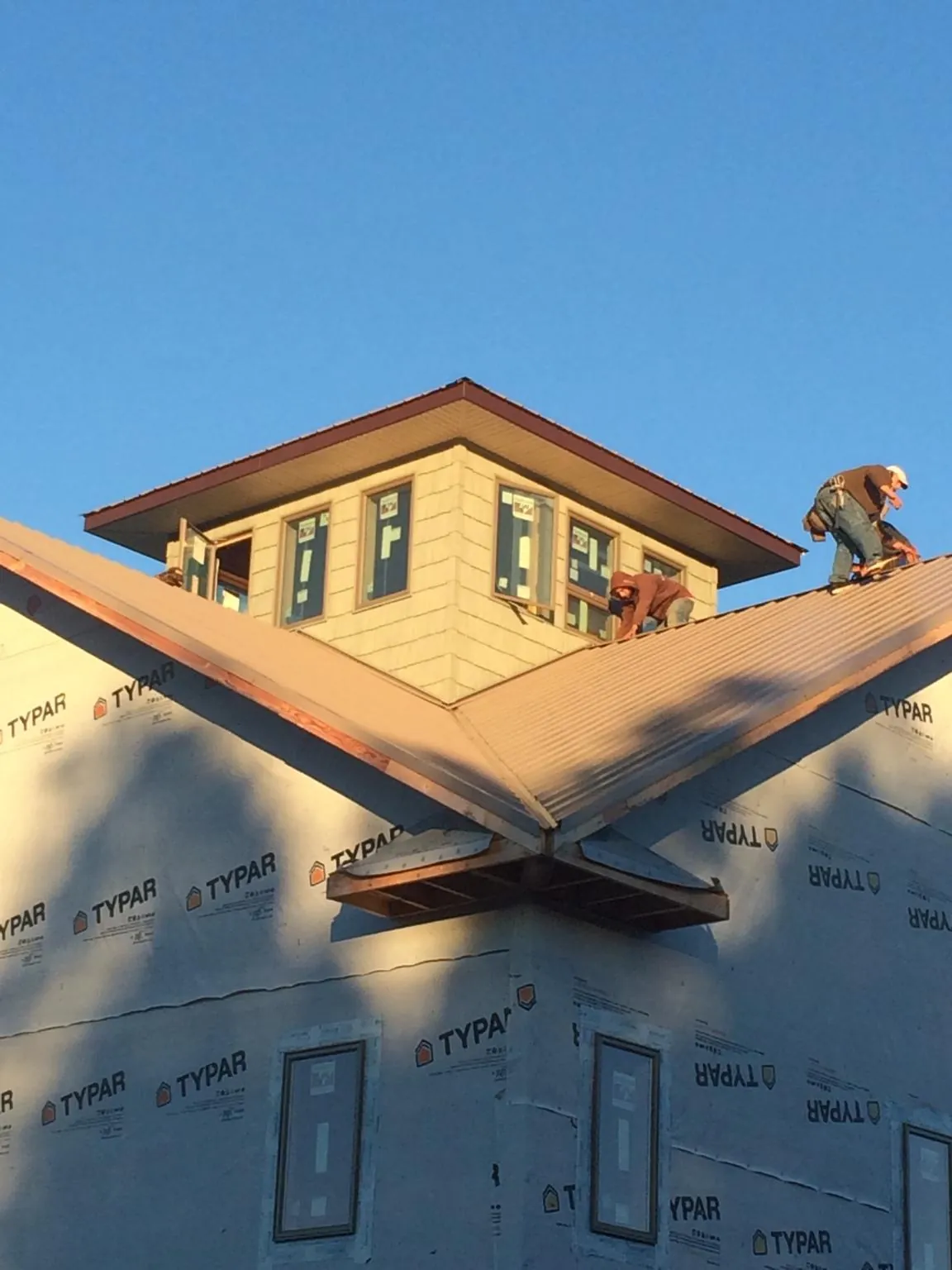 Roofers working around a rooftop cupola on a new metal roof at sunset — Roof Waterproofing in Bucyrus by Roofing Brothers